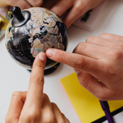 Children's hands pointing at globe